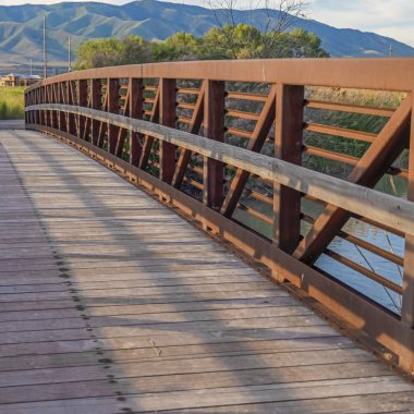 Kare çerçeve güneş ışığı ahşap güverte ve dağ manzaralı göl üzerindeki köprü korkulukları