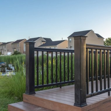 Kare çerçeveli, gölcüklü, köprü manzaralı ve arka planda evler ve gökyüzü olan Grassy Park