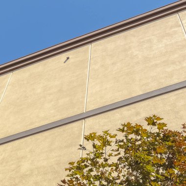 Kare çerçeve Bulutsuz mavi gökyüzüne karşı ağaçlarla aydınlık binanın dış yüzünü kapatın