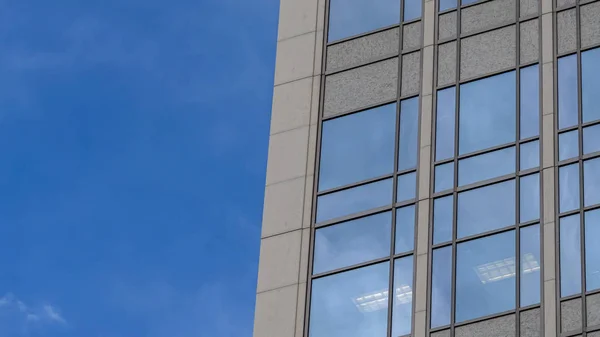Marco Pano Concéntrate en un moderno edificio exterior con ventanas de cristal que reflejan el cielo azul — Foto de Stock