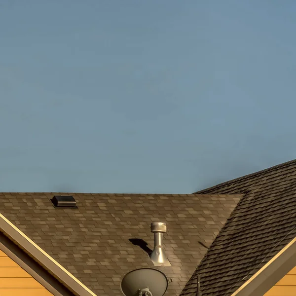 Eksterior Rumah persegi dengan atap shingles dan jendela bulat gable terhadap langit biru — Stok Foto