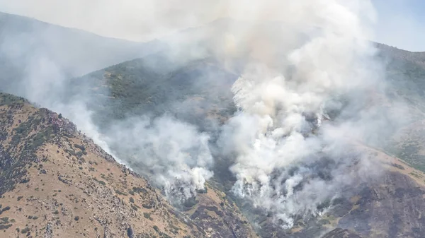 Cadre Pano Paysage naturel avec des bouffées de fumée blanche provenant d'un feu de forêt de montagne — Photo