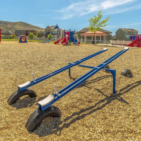 Square frame Bright blue see saw at a playground with Timpanogos Mountains and blue sky view