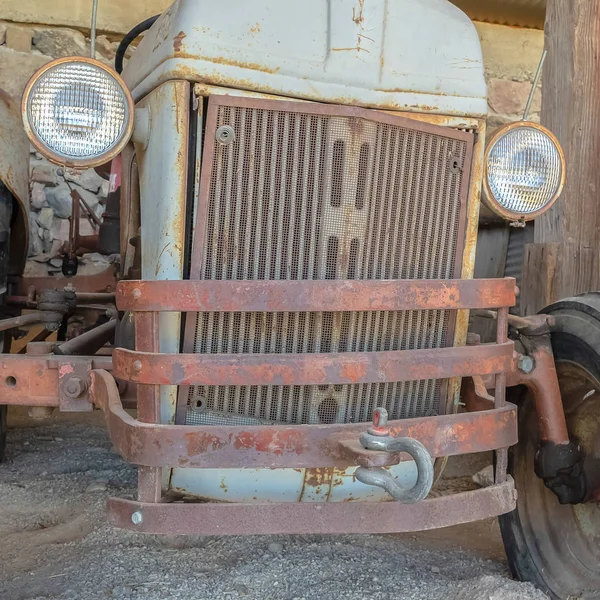 Vierkantrahmenfront eines alten Traktors gegen Steinmauer und Dach einer Scheune — Stockfoto