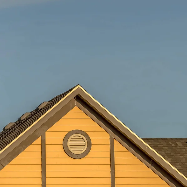 Cornice quadrata Casa esterna con tegole e finestra tonda a due falde contro il cielo blu — Foto Stock