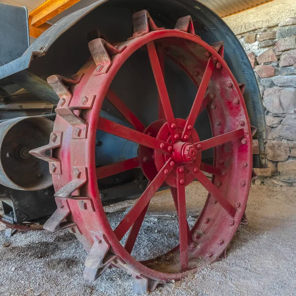 Квадратный красный колесный край винтажного трактора против каменной стены фермерского сарая — стоковое фото