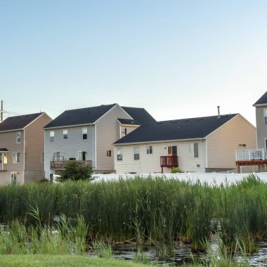 Kare çerçeve Yeşil çimenler ve gölet manzaralı bir parkta evler ve mavi gökyüzü arka planı