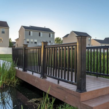 Gölcüklü kare çim parkı ve arka planda evler ve gökyüzü manzaralı köprü