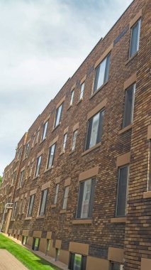 Tuğla duvar ve gri çerçeveli pencereleri olan eski klasik bir binanın dikey dış yüzeyi