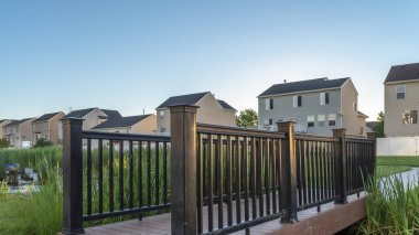 Pano çerçeveli Grassy Parkı, gölcüklü köprü, manzaralı evler ve arka planda gökyüzü