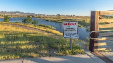 Güneşli bir günde, patikaları ve köprüsü olan sığ bir gölde atlama uyarısı yok.