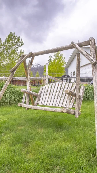 Vertikale Holzbank Schaukel auf dem üppigen Rasenhof eines Hauses mit weißem Lattenzaun — Stockfoto