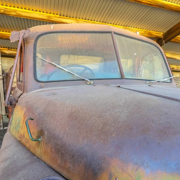 Старый винтажный автомобиль с ржавой и грязной крышей внутри гаража с металлической крышей — стоковое фото