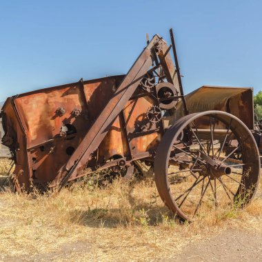 Eski ve eski bir traktörü ahşap çitlere ve açık mavi gökyüzüne yakın tutun.