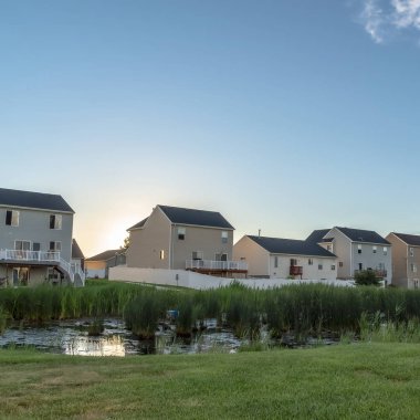Square Sunset in the suburbs with multi storey homes ovelookinga park with shiny pond