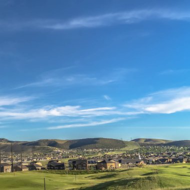 Square Golf course fairway and putting green with flagsticks under blue sky and clouds