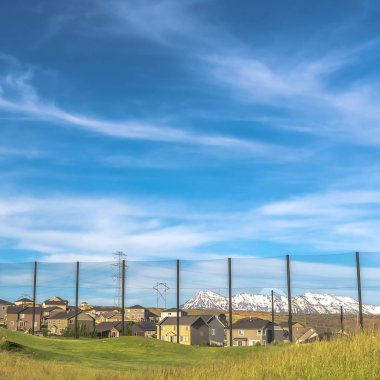 Square frame Golf course fence with homes and snow capped mountain in the scenic background