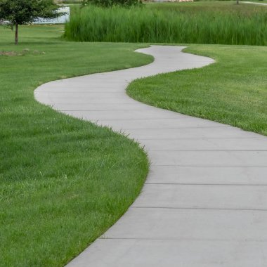 Kare Dar asfalt patika Parktaki yemyeşil çimlerin arasında kıvrılıyor