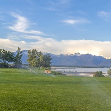 Kare çerçeve Göl ve kar kaplı dağ fıskiyeler ile yeşil çimenler ön planda