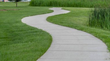 Pano çerçeve Dar asfalt patika Parktaki yemyeşil çimlerin arasında kıvrılarak oyun parkı ile