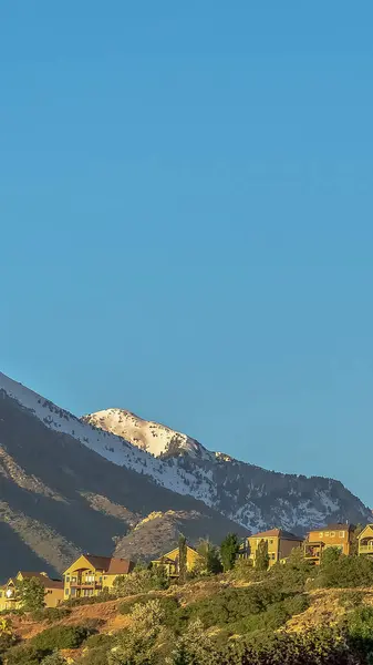 Cadre vertical Maisons sur une colline avec vue sur la montagne enneigée et ciel bleu sans nuages — Photo