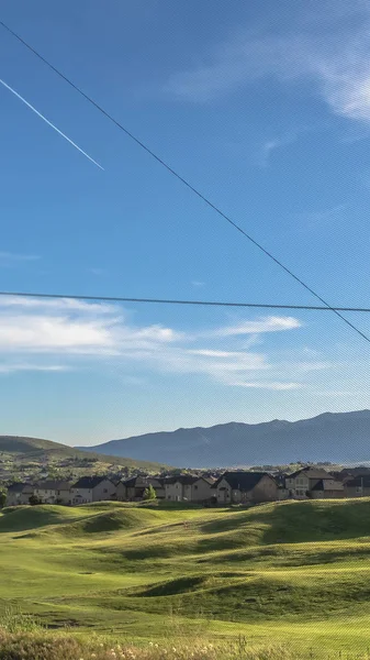 Κάθετο πλαίσιο Φράχτης με γραφική θέα των σπιτιών γήπεδο γκολφ και το βουνό σε μια ηλιόλουστη μέρα — Φωτογραφία Αρχείου