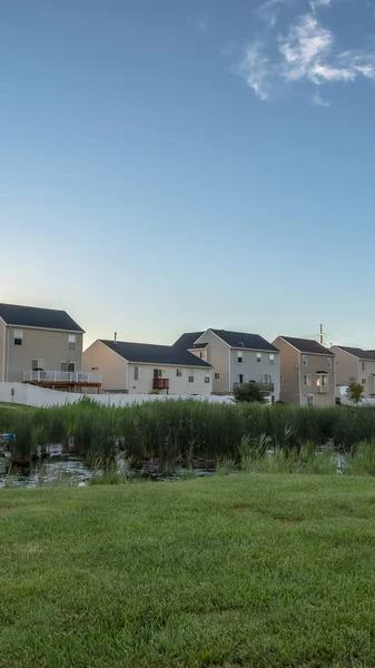 Puesta de sol vertical en los suburbios con casas de varios pisos ovelookinga parque con estanque brillante — Foto de Stock