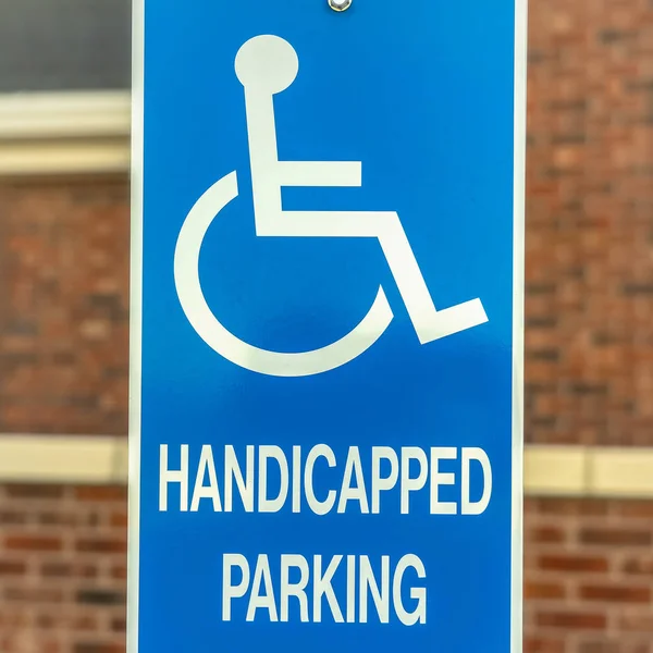 Plac Zbliżenie niepełnosprawnych Znak parkingowy przed rozmazaną czerwoną ceglaną ścianą kościoła — Zdjęcie stockowe