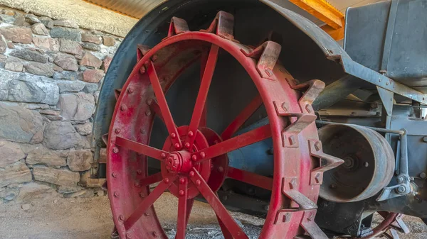 Пано Красное колесо обода и винтажный трактор против каменной стены фермерского сарая — стоковое фото