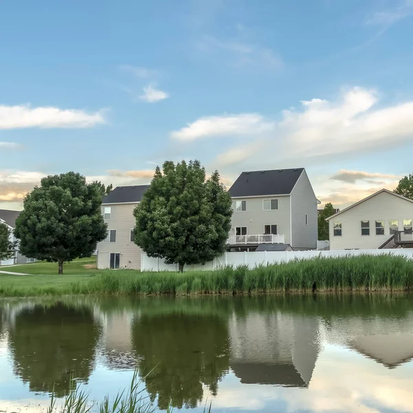 Marco cuadrado Paisaje suburbano escénico con casas y cielo nublado reflejado en un estanque brillante — Foto de Stock