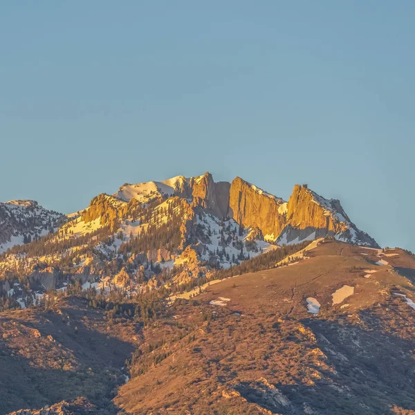 Cadre carré Pic de montagne frappant avec des pentes accidentées contre le ciel bleu par une journée ensoleillée — Photo