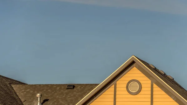 Pano House exteriör med tak bältros och runda gavel fönster mot blå himmel — Stockfoto