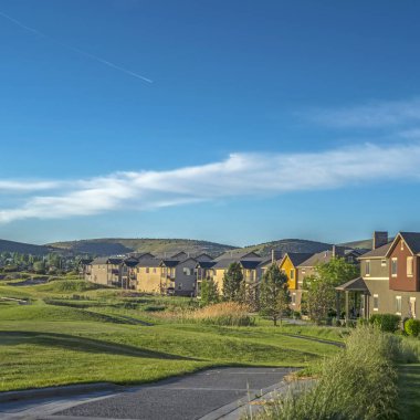 Dağ ve mavi gökyüzünün manzaralı arka planına sahip golf sahasının etrafındaki kare evler.
