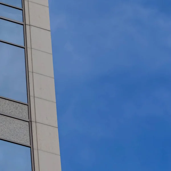 Square Focus en un moderno edificio exterior con ventanas de cristal que reflejan el cielo azul — Foto de Stock