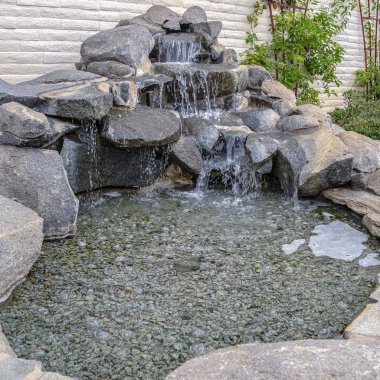 Güneşli bir günde çağlayan şelaleyle kare taş süsleme