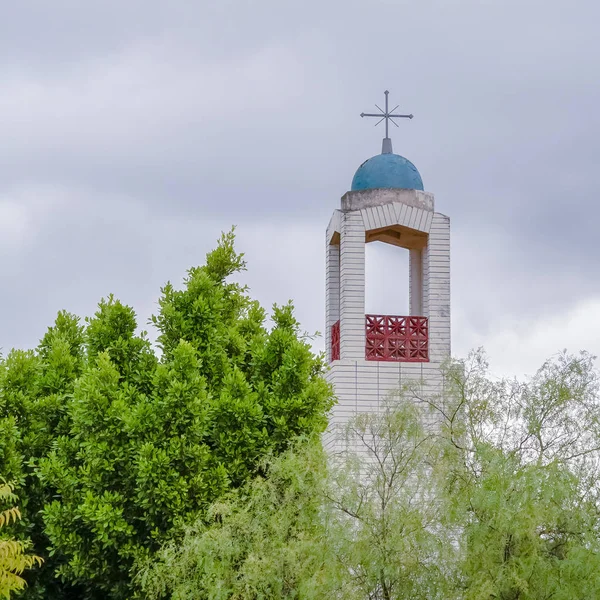 Clocher carré d'une église s'élevant au-dessus des arbres verts — Photo
