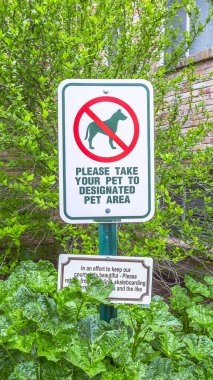 Dikey çerçeve Yapraklara ve tuğla duvarlara karşı binanın dışındaki bir evcil hayvan tabelasına odaklan