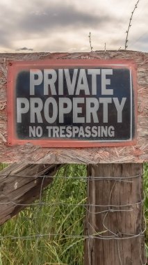 Vertical frame No Trespassing sign at a private property with old wire fence and metal gate
