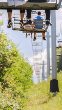 Vertical frame Chairlifts with tourists against trees and sky in park City Utah at off season