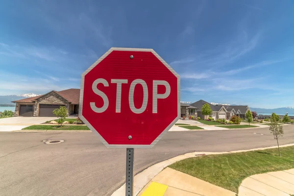 Selective focus of a red and white stop sign against paved road and houses — Stock Photo, Image