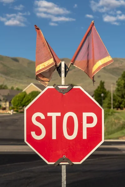 Stoppschild mit zwei roten Flaggen gegen Straße und Häuser — Stockfoto