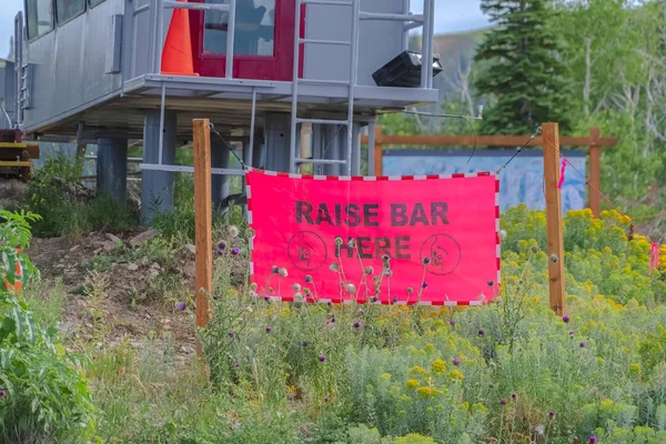Raise Bar Here sign against chairlift station in Park City Utah at off season