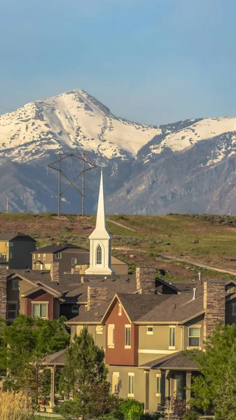 Pionowe domy i kościół z malowniczym krajobrazem góry z pokrywą śnieżną i błękitnym niebem — Zdjęcie stockowe