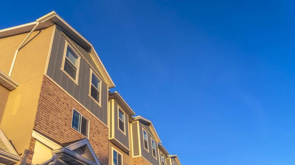 Panorama Exteriör av radhus ses mot pulserande blå himmel och snötäckta berg — Stockfoto