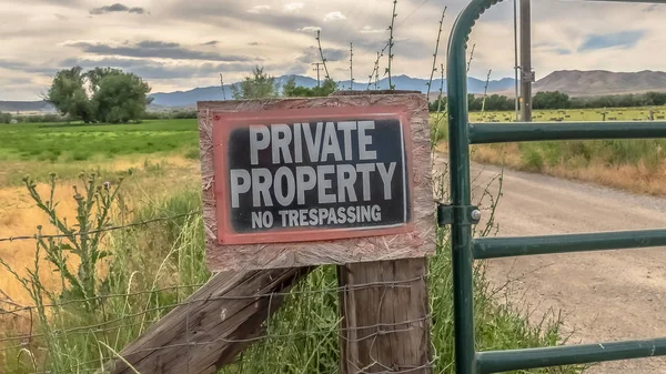 Panorama No Trespassing sign on the wire fence and green metal gate of private property — Stock Photo, Image