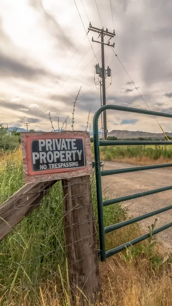Vertical frame Security gate and fence with No Trespassing sign against mountain and cloudy sky — Stock Photo, Image