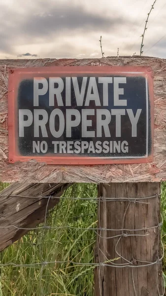 Vertical frame No Trespassing sign at a private property with old wire fence and metal gate