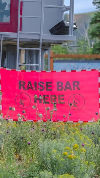Vertical Raise Bar Here sign against chairlift station in Park City Utah at off season