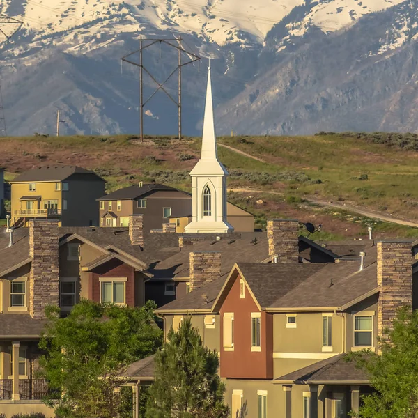 Casas cuadradas e iglesia con paisaje escénico de montaña nevada y cielo azul — Foto de Stock