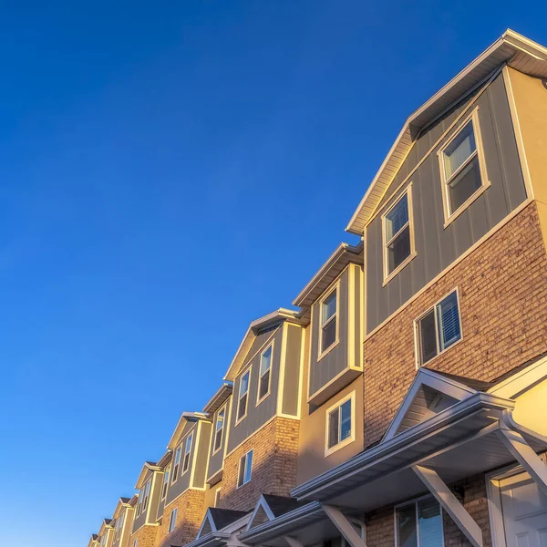 Exterior cuadrado de casas adosadas vistas contra el cielo azul vibrante y la montaña cubierta de nieve — Foto de Stock